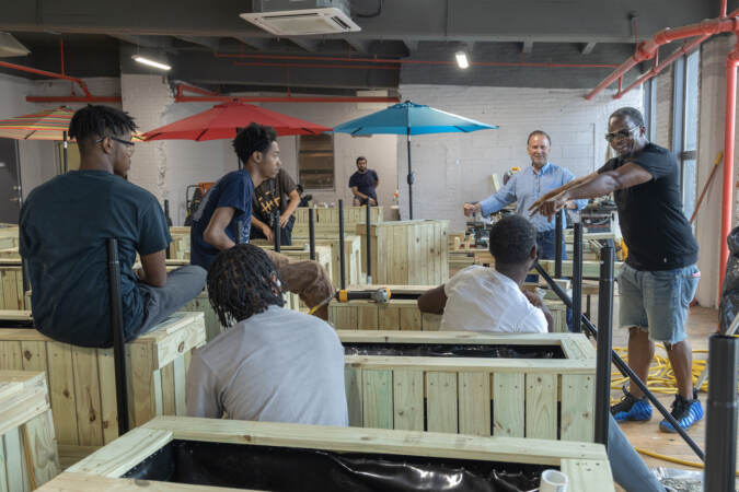 Oman Sewell (right) and Angelo Zaharatos (second from right) speak to young Philadelphians working on a construction project.