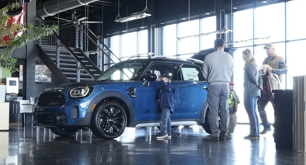 Potential buyers look at a 2023 Cooper Countryman S sports-utility vehicle on the floor of a Mini dealership on Friday, Feb. 17, 2023, in Highlands Ranch, Colo. Potential buyers look at a 2023 Cooper Countryman S sports-utility vehicle on the floor of a Mini dealership on Friday, Feb. 17, 2023, in Highlands Ranch, Colo.