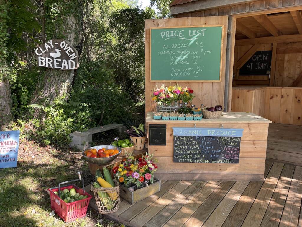 A farm stand with a sign that reads Clay Oven Bread