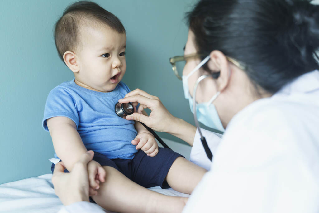Asian Female Doctor Using Stethoscope For Checking Heart Beat An Doctor using a stethoscope on an infant.