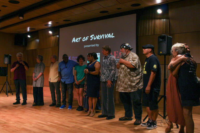 Artists involved with the Kensington Storefront stand at the front of a room.