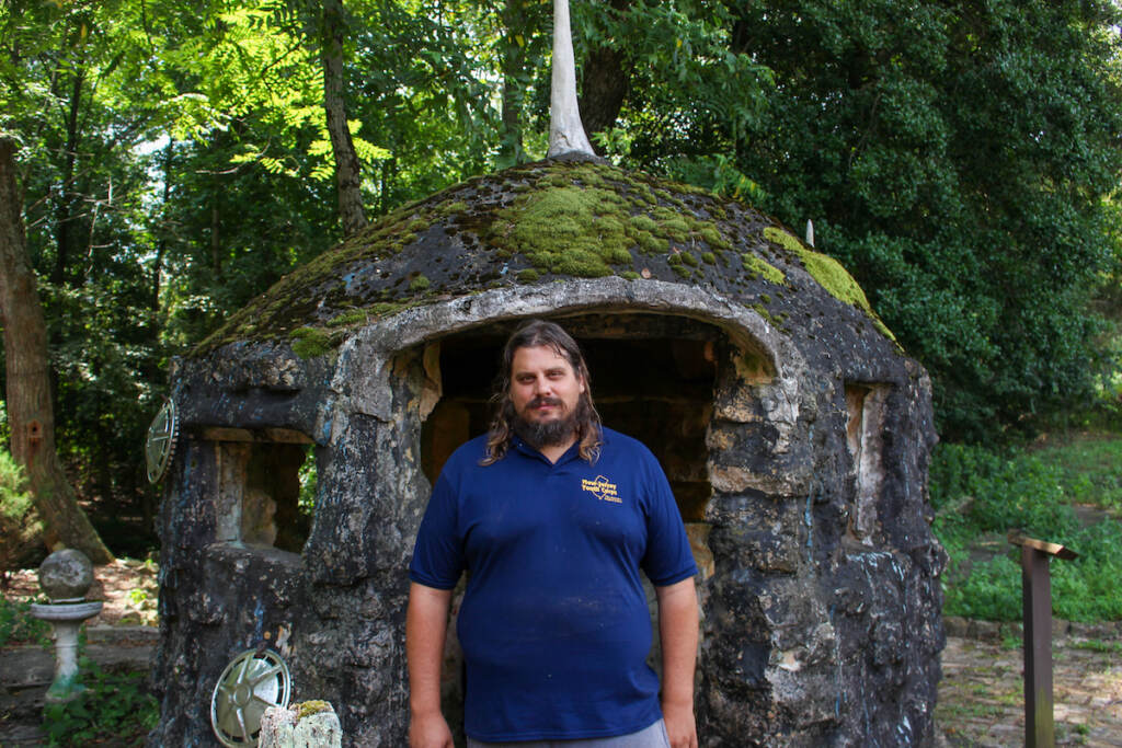 Steven Medio poses for a photo in front of a stone structure.