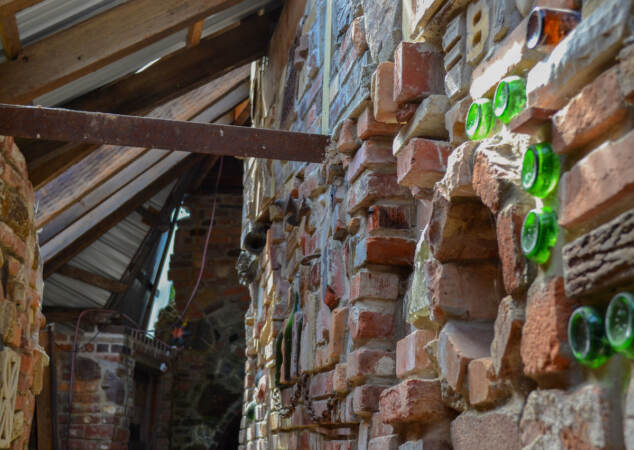 Bottles are embedded in a wall of bricks.