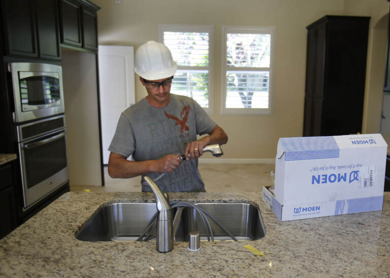 A plumber installs a kitchen faucet on a home under construction in Sacramento, Calif. (AP Photo/Rich Pedroncelli)