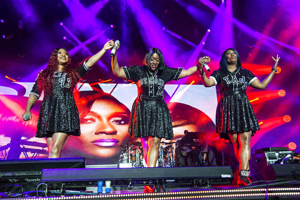 Members of SWV raise their hands together onstage.