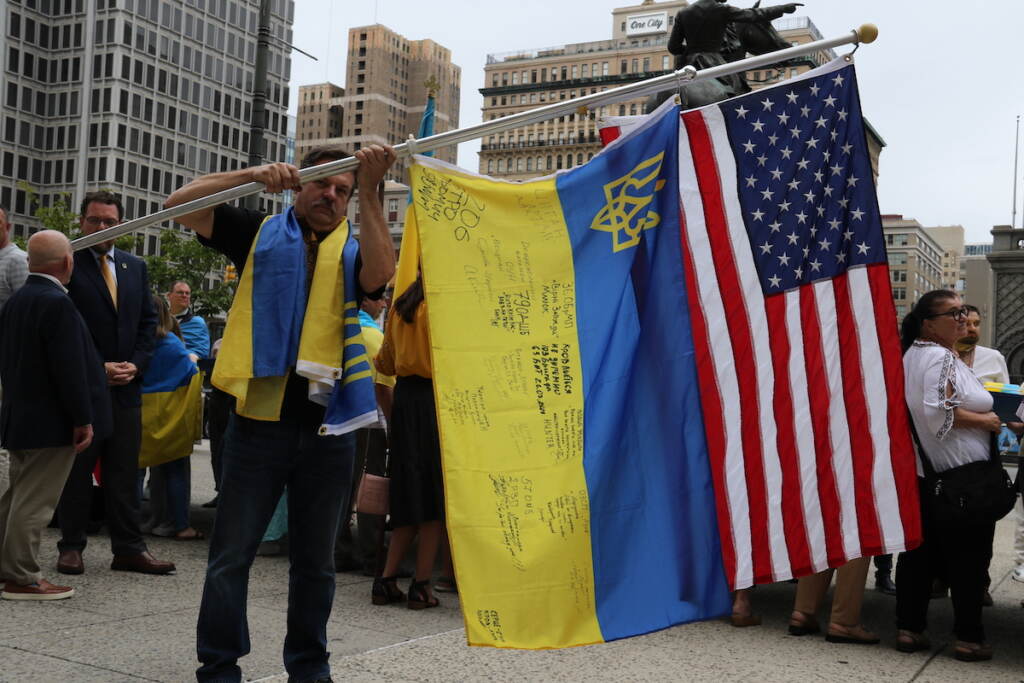 Ukrainian and American flags are held up together.