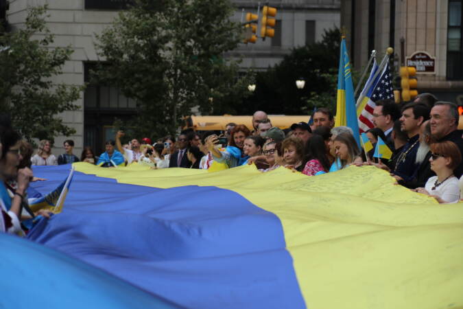 Attendees hold a huge Ukrainian flag.