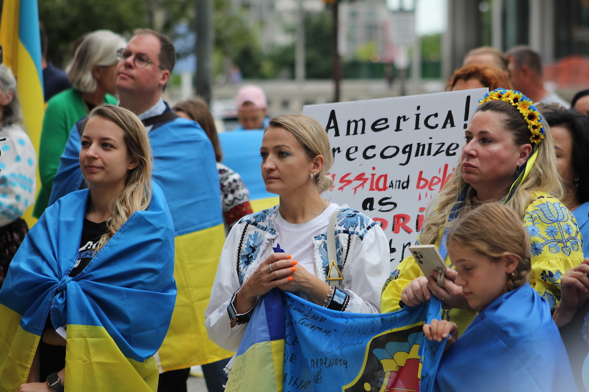 People draped in Ukrainian flags and wearing blue and yellow clothes stand together.