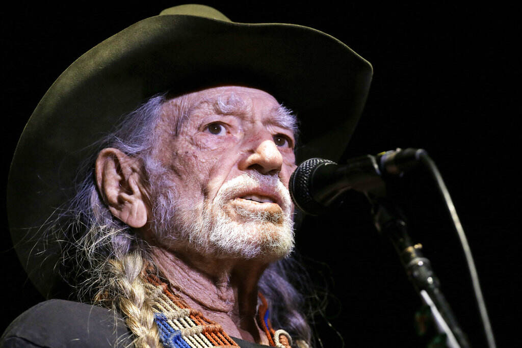 Willie Nelson sings into a microphone.