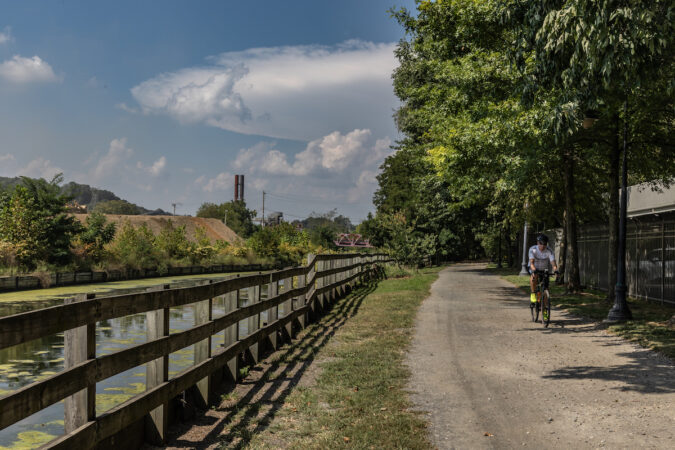 A biker rides along a bike path near a body of water.