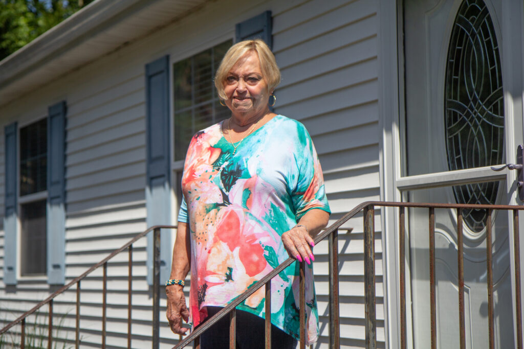 Phyllis Blackiston stands on a stairway in front of a door of her former house in Millsboro.
