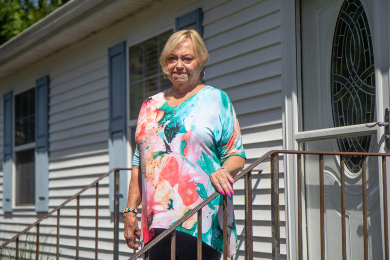 Phyllis Blackiston stands on a stairway in front of a door of her former house in Millsboro.