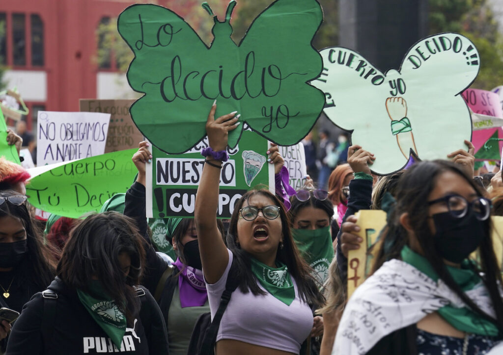 A woman holds up a sign with a message that reads in Spanish; 