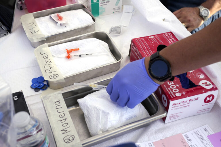 Syringes with vaccines are prepared at the L.A. Care and Blue Shield of California Promise Health Plans' Community Resource Center where they were offering members and the public free flu and COVID-19 vaccines Oct. 28, 2022, in Lynwood, Calif. Updated COVID-19 vaccines in the latter half of 2023 come just in time to pair them with flu shots. (AP Photo/Mark J. Terrill, File)