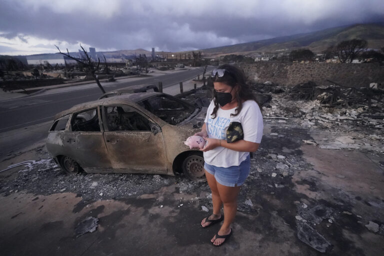 Summer Gerling picks up her piggy bank found in the rubble of her home following the wildfire on Aug. 10, 2023, in Lahaina, Hawaii