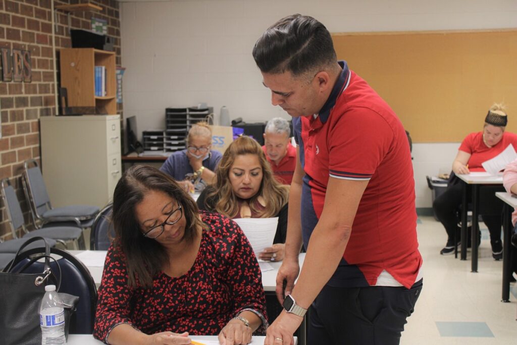 Launcher A teacher looks at a students' work on the desk in front of her.