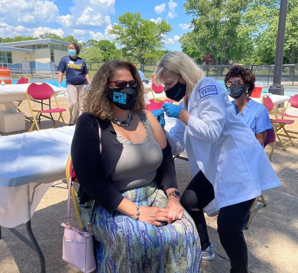 Bethany Hall-Long giving someone a vaccine outdoors