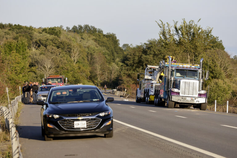 A car and emergency responders by the side of the road.