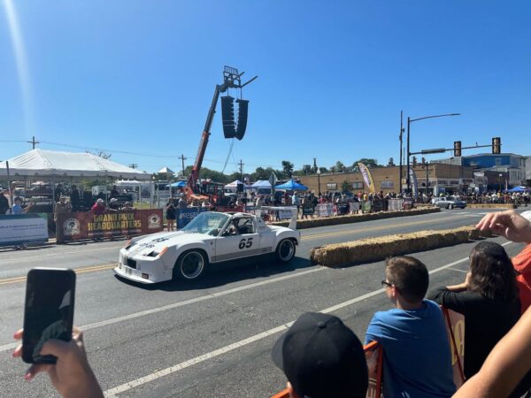 A car drives by on a street as spectators watch