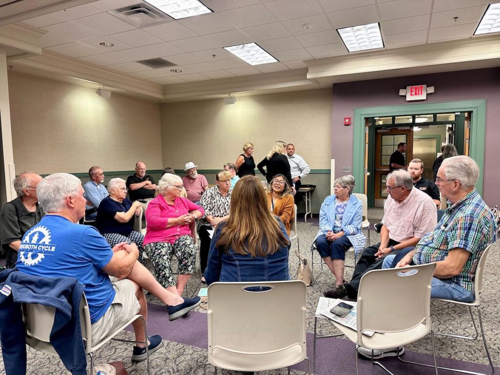 del-highway-deaths-town-hall-1 People sit together in a circle at a town hall.