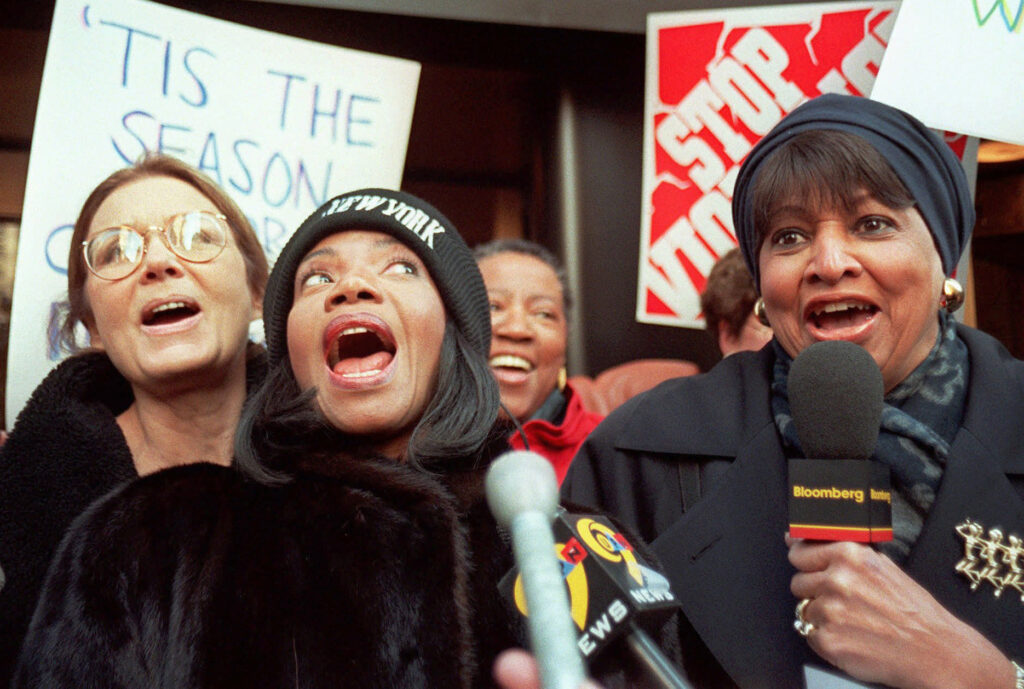 C. DeLores Tucker (right) joins Gloria Steinem (far left) and Melba Moore (center) to sing during a protest against lyrics they say promote violence against women outside Time Warner offices in New York on Dec. 18, 1997. (AP Photo/Michael Schmelling)