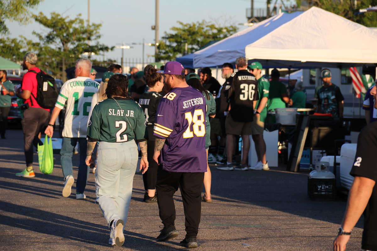 One person wearing a Vikings jersey walks among a crowd of Eagles fans.