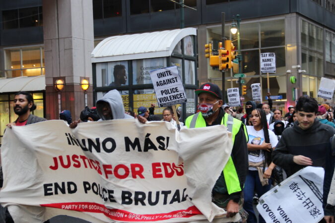 Protesters march holding signs demanding justice for Eddie Irizarry.