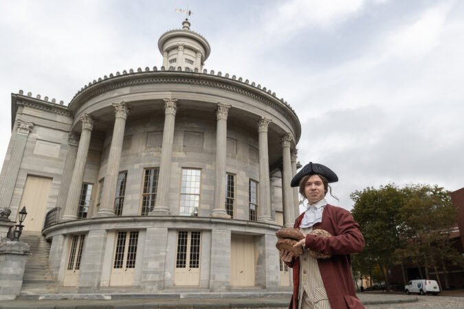 A Benjamin Franklin re-enactor poses for a photo in front of a building in Old City