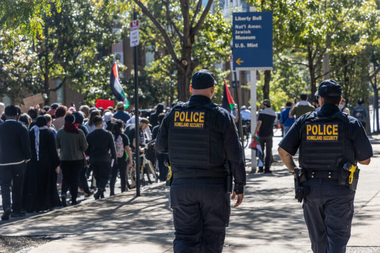 Homeland Security officers walk next to the marchers
