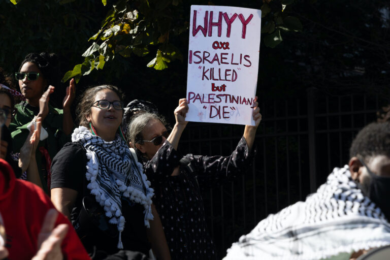 A person holds a sign criticizing WHYY at the protest