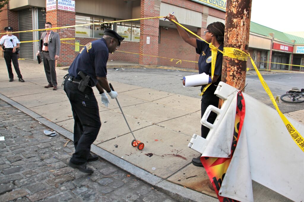 Police officer cleaning up at a crime scene after a shooting.