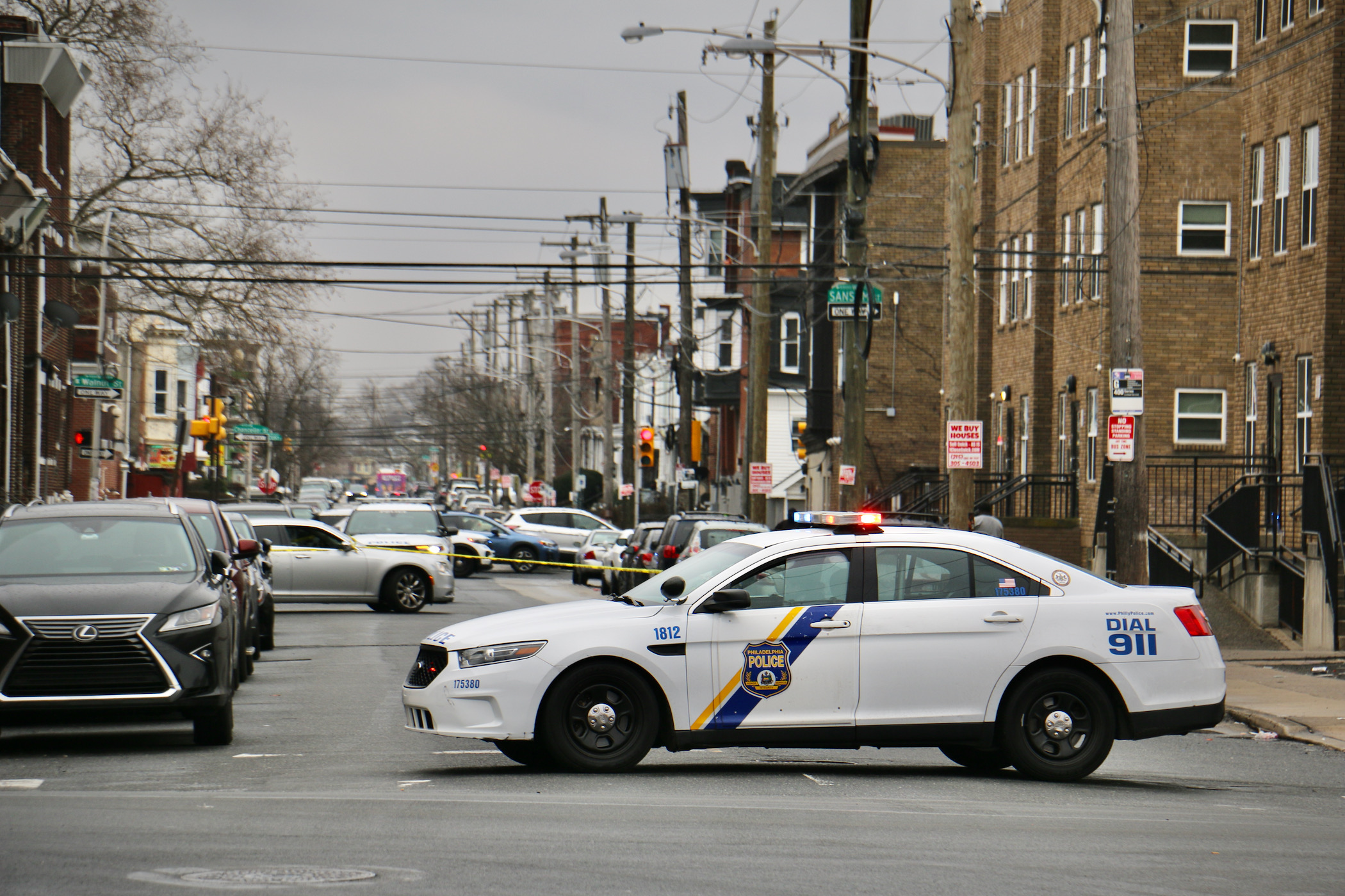 2023 01 31-e lee-philadelphia 56th and sansom-shooting police car A police car parked in the middle of the road with a crime scene in the background.
