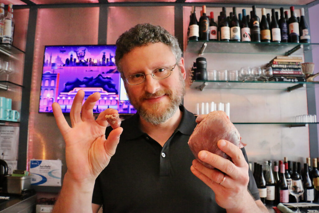 2023 06 20-e lee-jonathan reisman-south philadelphia-jet wine bar organ meat and wine pairing hearts Dr. Jonathan Reisman holds up a chicken heart and a pig heart for comparison