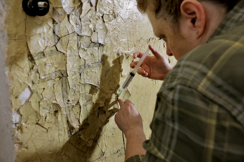 Stephanie Hoagland works to preserve a cross drawn into a wall