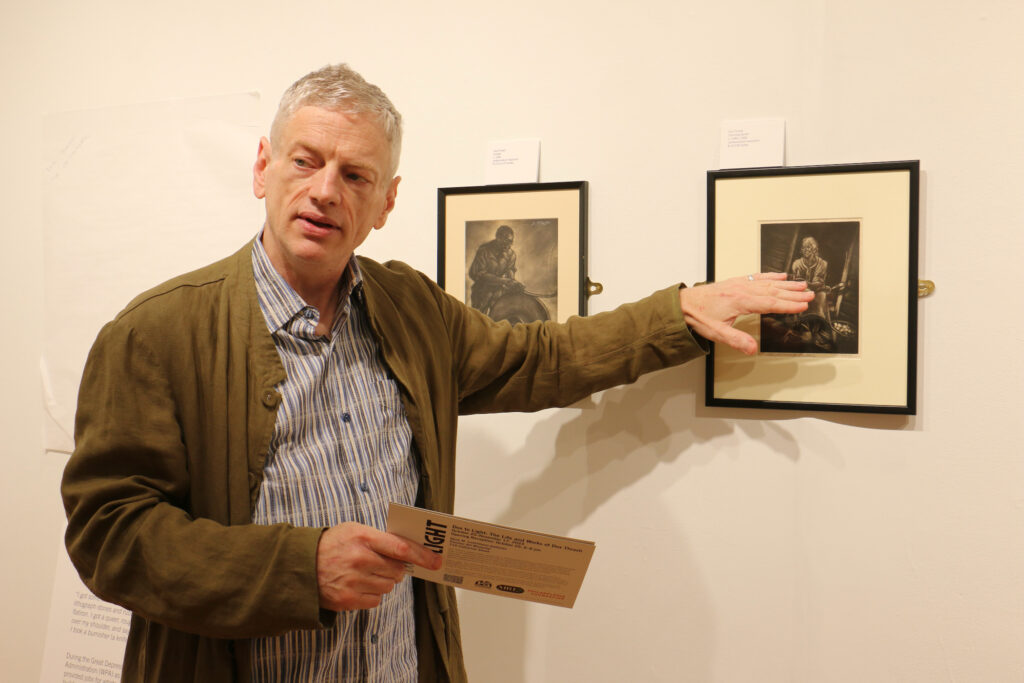 Ron Rumford points towards a print on the wall by Dox Thrash.