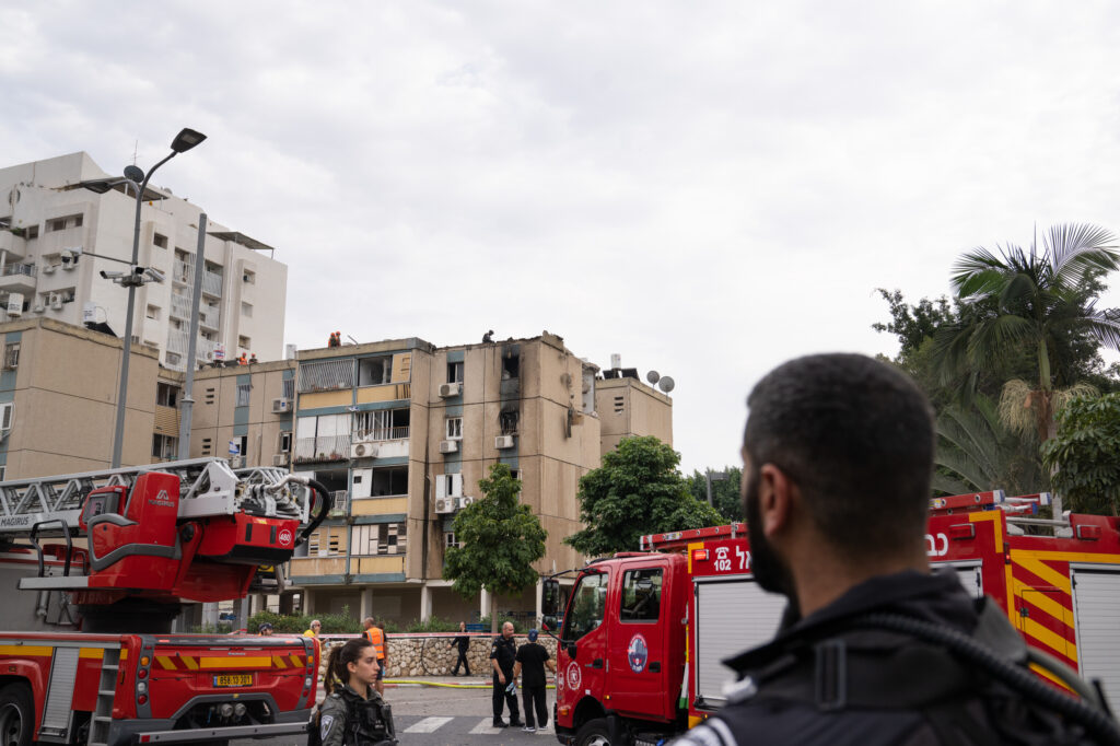 First responders at the site of a rare rocket strike in Tel Aviv that hit a residential building on Friday. On Friday in the Gaza city of Khan Younis, people collect the bodies of Palestinians killed in airstrikes.