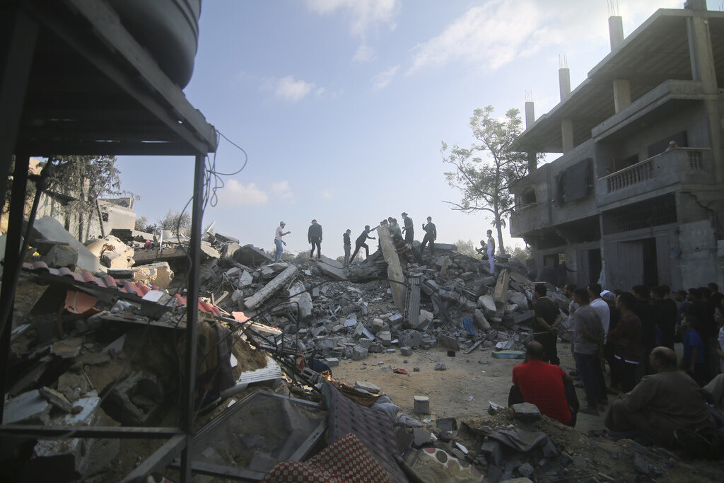 Palestinians stand by the building destroyed in an Israeli airstrike