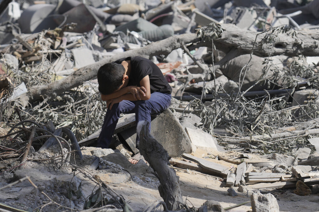 AP23291433049839 A Palestinian boy sits on the rubble of the building destroyed in an Israeli airstrike in Bureij refugee camp Gaza Strip, Wednesday, Oct. 18, 2023. (AP Photo/Hatem Moussa)