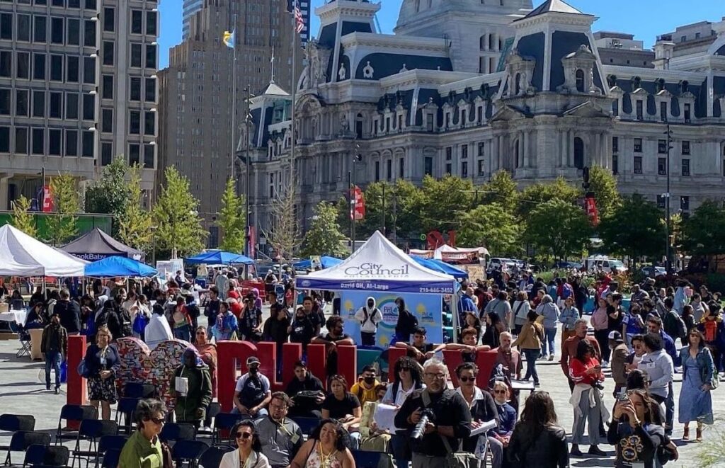 LABF p2 A view from above of a crowd of people and stands in LOVE Park. Philadelphia City Hall is visible in the background.