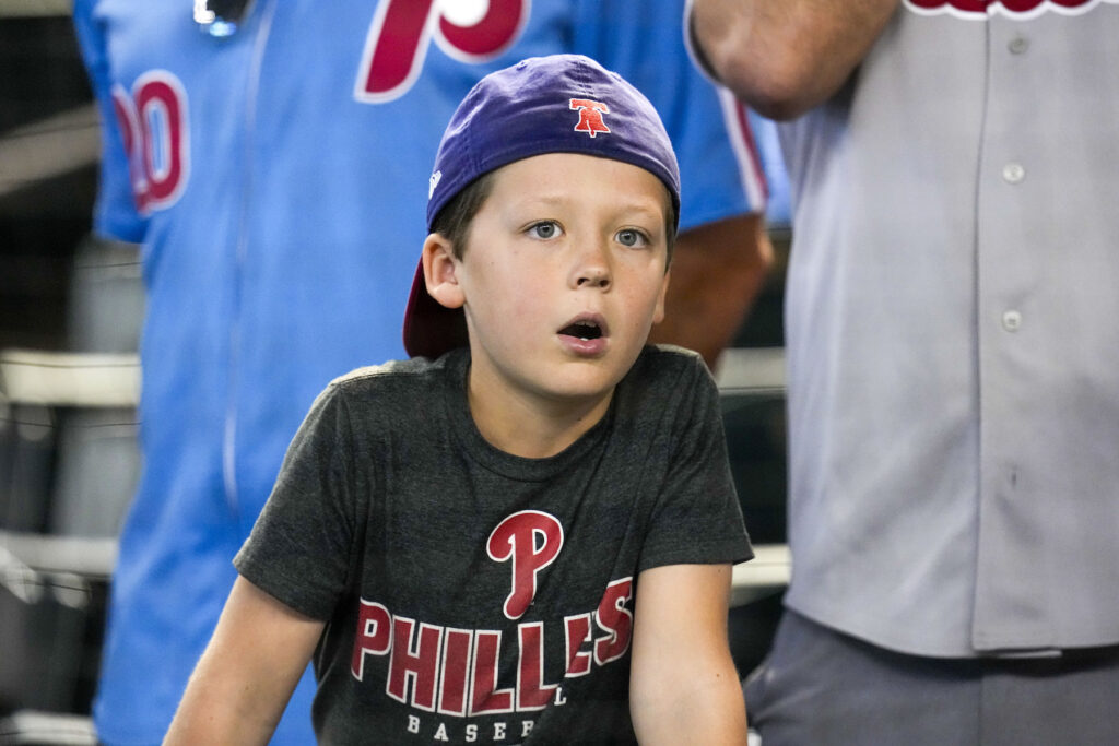 A young boy wearing Phillies hat and shirt at the game.