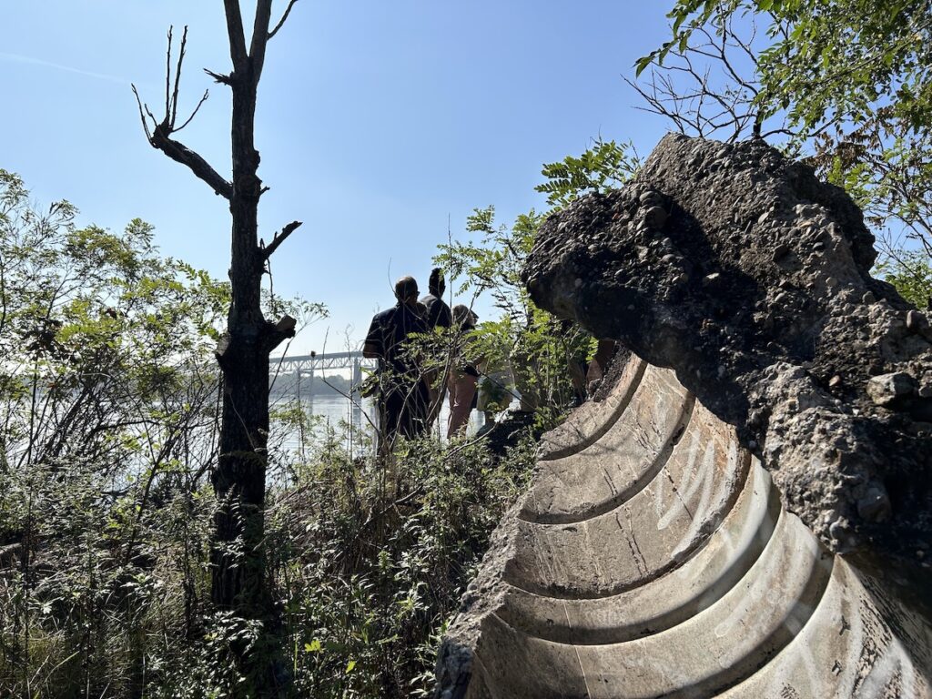 A hunk of concrete. Beyond it, the river and people standing
