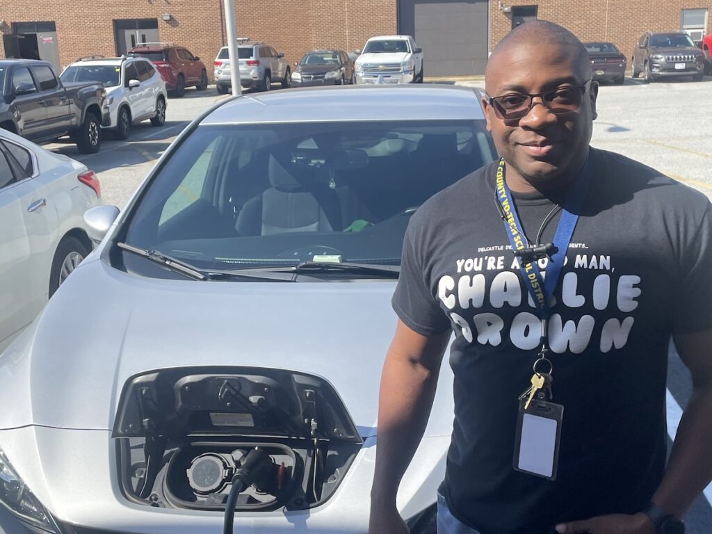 delcastle-ev-1 Chris Langhorn poses for a photo in front of his electric vehicle while it's charging.