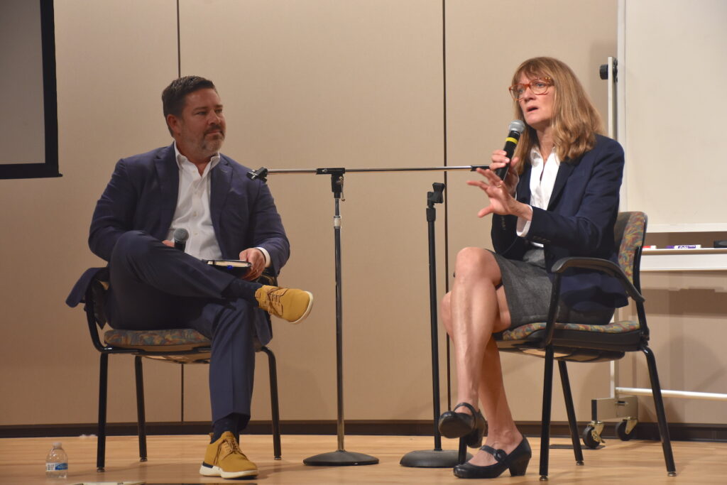 2 people sitting on a stage talking into microphones