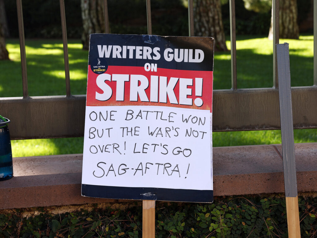 Actors Continue To Strike As Writers’ Deal With Studios Nears Completion A WGA support sign rests near SAG-AFTRA members picketing outside Warner Bros. Studio as the actors strike continues on September 26, 2023 in Burbank, California. (Mario Tama/Getty Images)