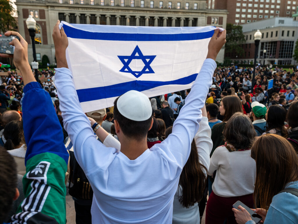 A man holds up an Israeli flag overlooking a pro-Gaza rally at Columbia University on Thursday.