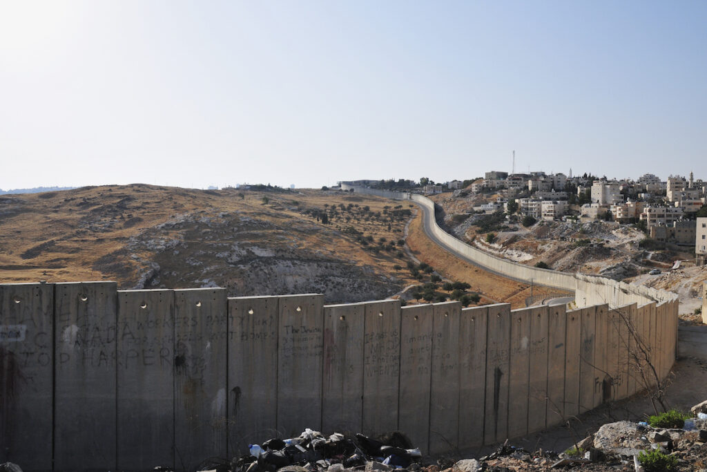 A view of the barrier wall separating Abu Dis from an open filed on the edge of Jerusalem