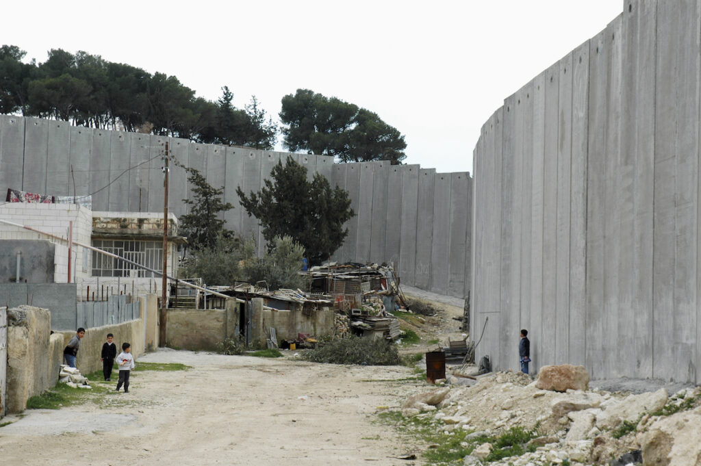 Children play near the Israeli barrier wall