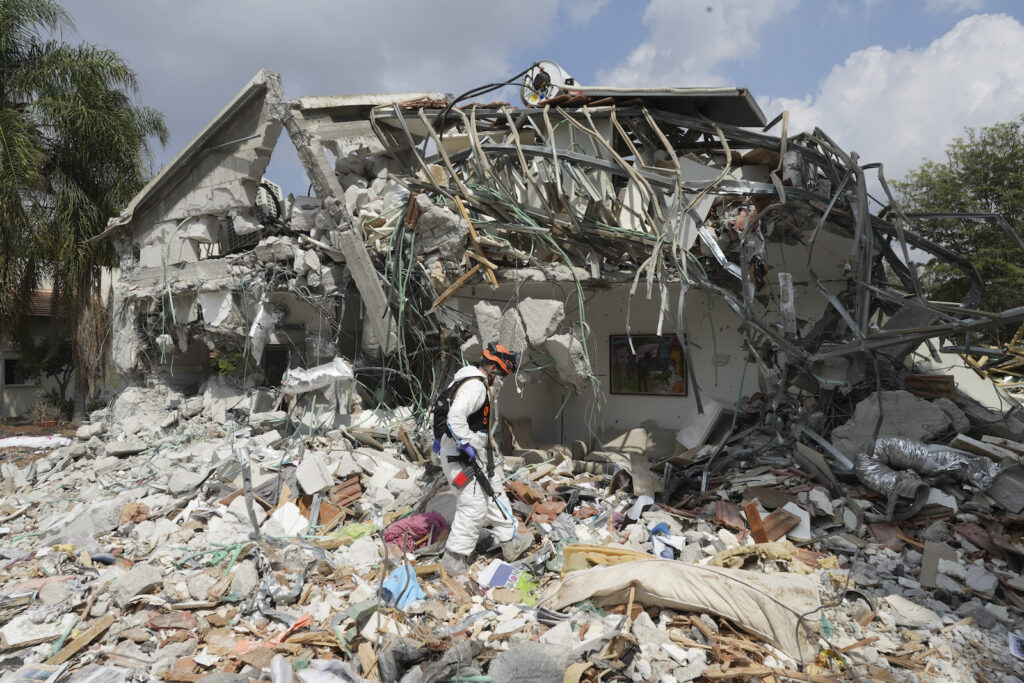 APTOPIX Israel Palestinians An Israeli soldier walks by a house destroyed by Hamas militants in Kibbutz Be'eri