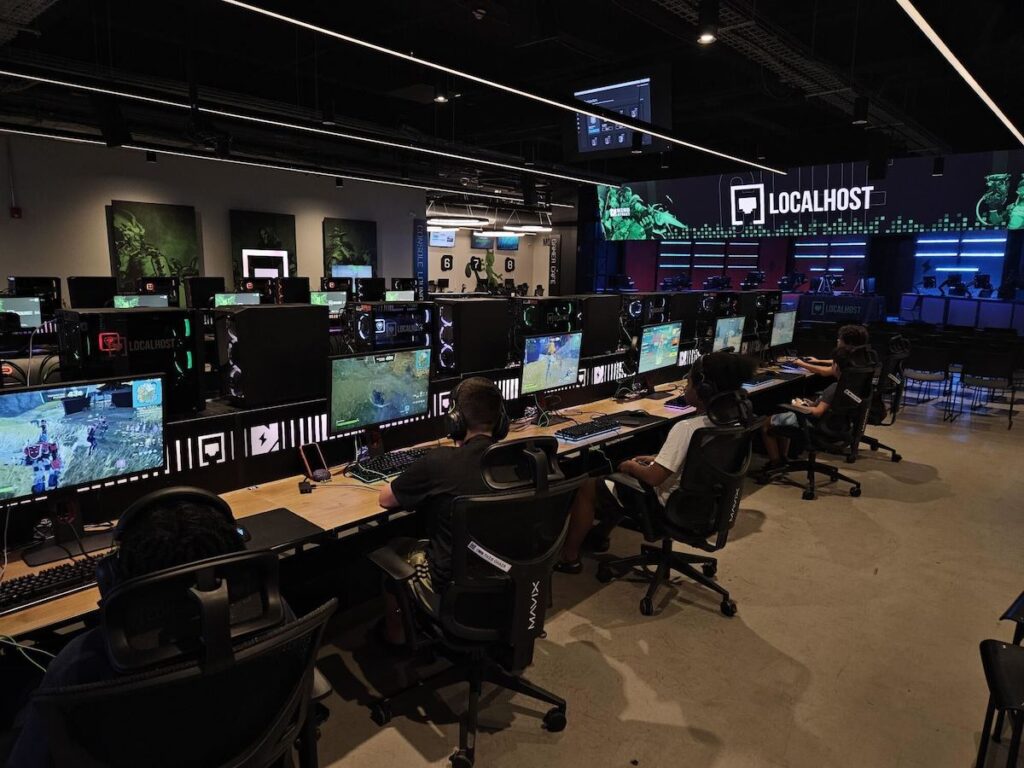 Kids play games at a row of stations in a gaming center.