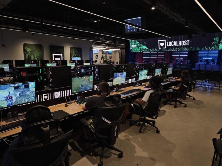 Kids play games at a row of stations in a gaming center.